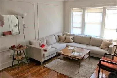 A furnished living room with a sectional sofa and low wooden coffee table in an Apartments 4 Yale rental