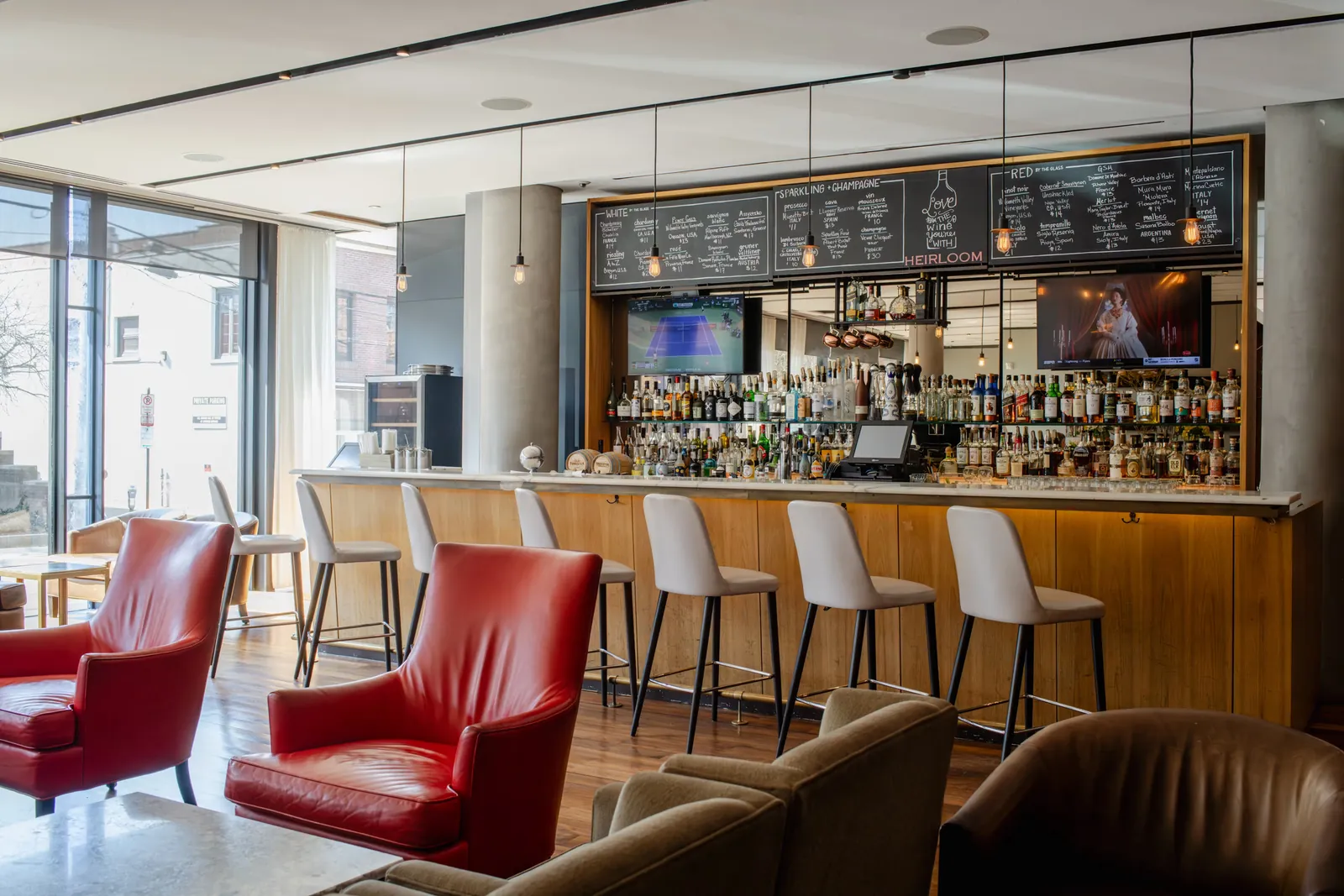 The bar at Heirloom, red leather armchairs and pale stools along a marble counter, chalkboard wine lists hung above the bottles