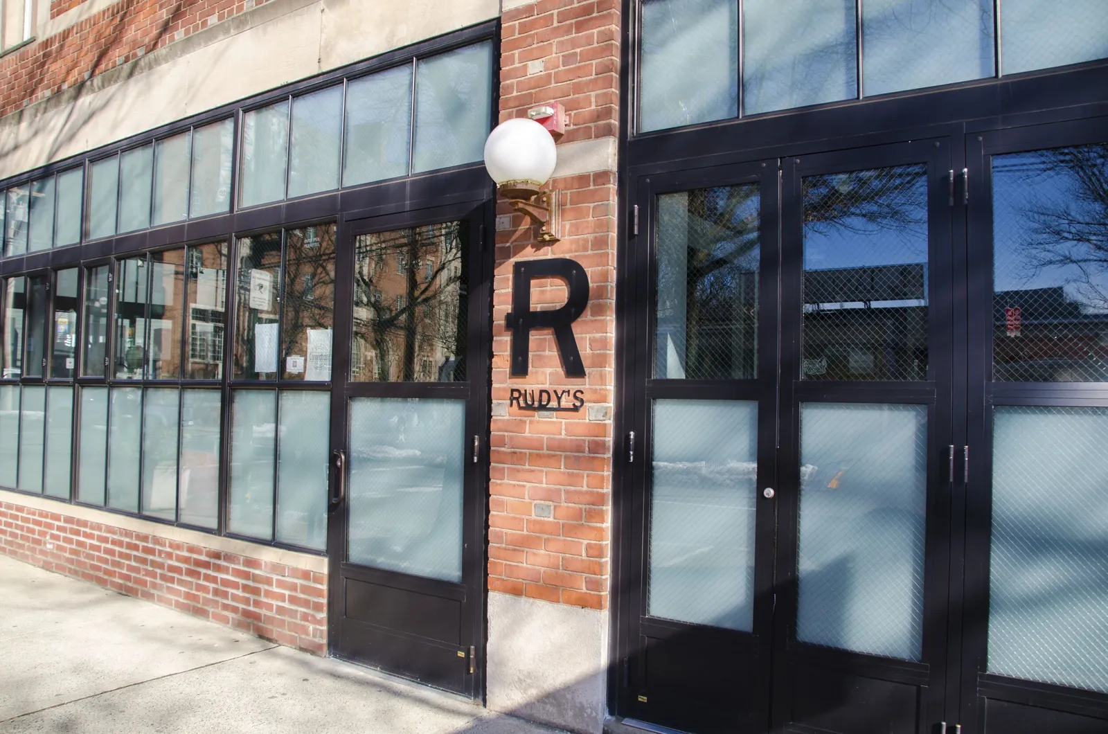 The brick corner facade and tall black doors of Rudy's