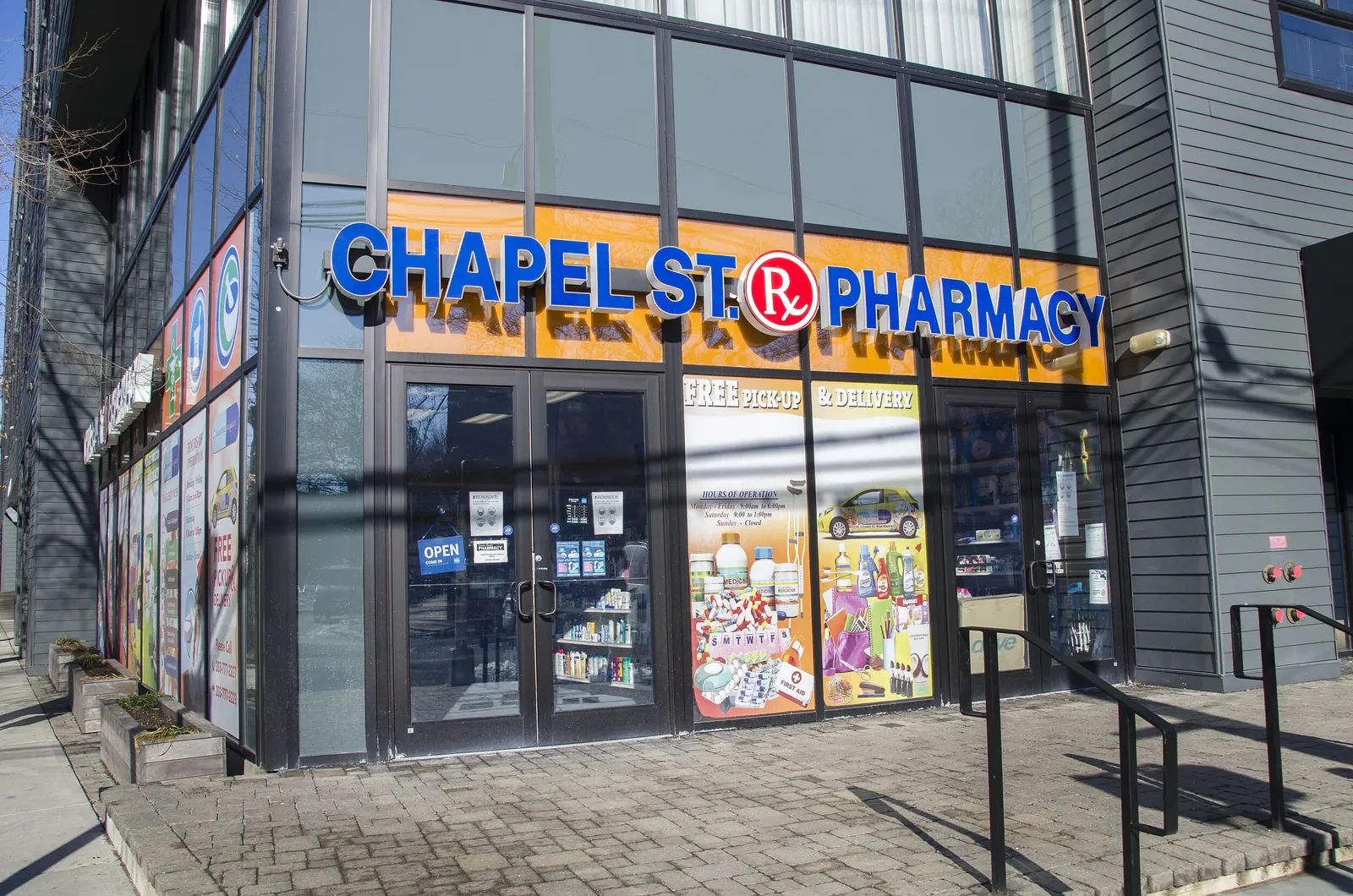The blue illuminated storefront sign of Chapel St. Pharmacy