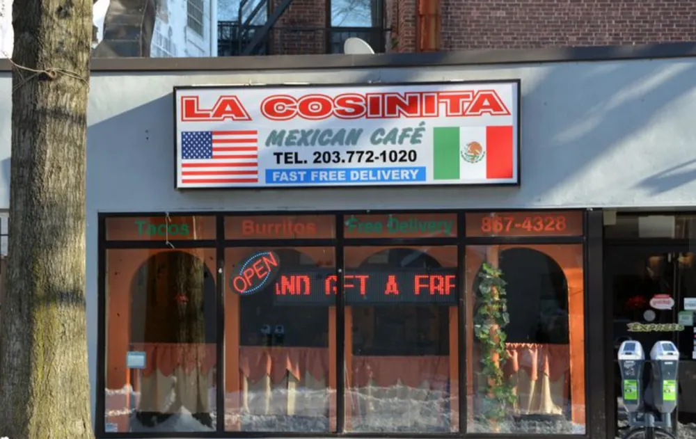 La Cosinita Mexican Cafe's red and white sign above its arched windows, an open sign lit in the glass