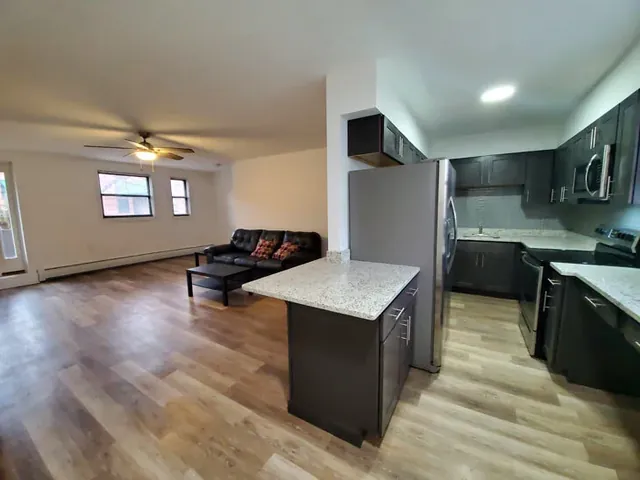 An open plan apartment kitchen and living area with wood floors in a Chelsea Company property