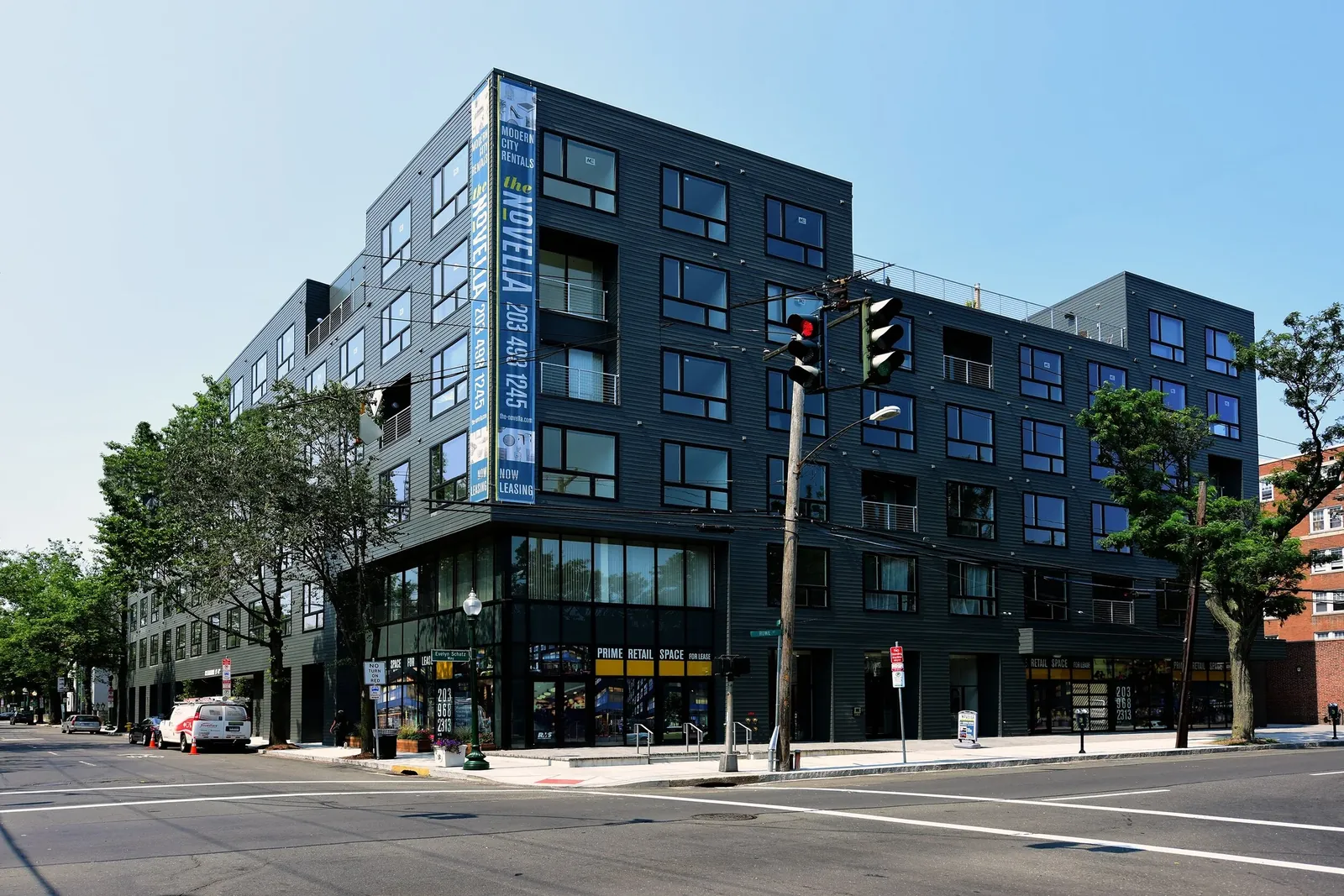 The Novella's modern apartment building on a street corner, seen from across the intersection
